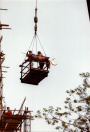 Exterieur, 06-1985. Twee mannen plaatsen een, hier nog ingepakte, enorme bladgouden piron met halve maan op de minaret, waarmee het hoogste punt van de attractie is bereikt.