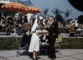 Kelder en serveerster op het terras van het <a href="/lemma/Caf%C3%A9-Restaurant" title="Café-Restaurant">Café-Restaurant</a> in <span class="redlink">1954</span>
