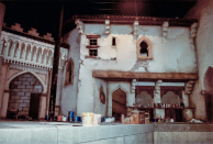 Tweede Marktscène, 05-1985. De tweede marktscène, gezien vanuit de vaargeul tegenover de tapijtenverkoper, richting de balie van de marktkoopman. De scène is in de afrondende fase van het schilderwerk en decoratie. De kolom aan de linkerzijde wordt later aangekleed als reusachtige palmboom.