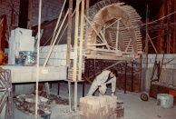 Krokodillentunnel, 03-1985. Cees Bouwens metselt aan een overstekende bakstenen wand vlak boven het wateroppervlakte in de krokodillentunnel, om zo de aanstaande bocht die de boten maken te verhullen. De ruimte die we hier rechts van de tunnel zien, kan worden beschouwd als loze ruimte. Bij oplevering van de attractie worden de ronde tunnelbuis en omliggende ruimtes voorzien van een houten plafond - een van de grootste loze ruimtes binnen de attractie waarvan, vanwege de beperkte draagkracht, het niet de bedoeling is dat je er overheen loopt.