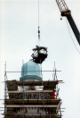 Exterieur, 06-1985. Twee mannen plaatsen een, hier nog ingepakte, enorme bladgouden piron met halve maan op de minaret, waarmee het hoogste punt van de attractie is bereikt.