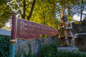 Toegang tot de <a href="/lemma/Indische_Waterlelies" class="mw-redirect" title="Indische Waterlelies">Indische Waterlelies</a>. Op de achtergrond één van de wachters. Het wegwijzer heeft het opschrift: &quot;Naar de grot der Indische Waterlelies, waar iedere vijf minuten de betoverde elfjes dansen&quot;.
