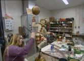 Vermoedelijk stagiaire werkend aan de <a href="/lemma/Pierrotmolen" title="Pierrotmolen">Pierrotmolenfiguur</a> in de werkplaats van <a href="/lemma/Decoratie_%26_Vormgeving" title="Decoratie &amp; Vormgeving">Decoratie &amp; Vormgeving</a> in <a href="/lemma/2001" title="2001">2001</a>