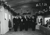 Tentoonstelling <a href="/lemma/S.L.E.M." title="S.L.E.M.">S.L.E.M.</a> 1953; interieur paviljoen Kaatsheuvel, ontworpen door Anton Pieck. Aan het plafond kenmerkende kroonluchters en achter aan de muur een tekening van de <a href="/lemma/Prinsenpoort" title="Prinsenpoort">Prinsenpoort</a>.