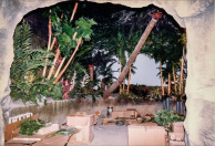 Jungle, 01-1986. Zicht op de jungle vanaf de ingangsrots. Veel kunstgroen in kartonnen dozen, afgewisseld met echte palmboomstammen en bamboestammen geïmporteerd uit de Filipijnen. Enkele stammen lopen door in de vaargeul, in pvc pijpen om rotting tegen te gaan.