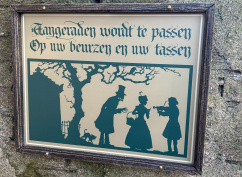 <a href="/lemma/Aangeraden_wordt_te_passen..." title="Aangeraden wordt te passen...">Aangeraden wordt te passen...</a>-bordje bij <span class="redlink">Danse Macabre</span>. Een vioolspeler leidt een vrouw af terwijl een verkleed skelet iets uit haar mand probeert te stelen, ook zichtbaar zijn een katje en het mausoleum van <a href="/lemma/Joseph_Charlatan" title="Joseph Charlatan">Joseph Charlatan</a>.