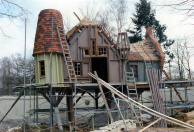 Het Lachhuys in aanbouw. Het houtwerk van de verschillende bouwdelen is elk in een andere kleur grondverf gezet. De leien liggen maar het riet moet nog aangebracht worden.