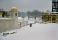 Exterieur, 02-1985. Tussen november en februari is de volledige buitengevel opgebouwd en al grotendeels afgewerkt, nu bedekt met een laagje sneeuw. Rechts de minaret, met een metalen ladder in de constructie om bovenin te geraken. De grote lichtgele koepel is die van de Bazaar. In de achtergrond een bouwkraan ter hoogte van de Bob in aanbouw, door het raam in het oker torentje voorin zie je een baandeel van de Bob.