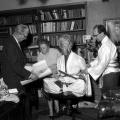 Vermoedelijk een kledingdoorpas van <a href="/lemma/De_Vliegende_Fakir" title="De Vliegende Fakir">De Vliegende Fakir</a>, bij <a href="/lemma/Peter_Reijnders" title="Peter Reijnders">Peter Reijnders</a> thuis in <a href="/lemma/Eindhoven" title="Eindhoven">Eindhoven</a>. Naast Reijnders zijn vrouw, daarnaast een ongedecoreerd model van de Fakir en rechts een onbekende man die waarschijnlijk &#039;om te zien hoe het werkt&#039; zelf ook een Fakir-pak (voor de &#039;andere&#039; Fakir) heeft aangetrokken. Jaren vijftig.