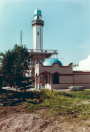 Exterieur, 06-1985. Schilders werken aan de Bazaar. De bomen die hier rondom de Bazaar en de minaret staan worden later nog verwijderd, vermoedelijk omdat het afbreuk doet aan het zicht op en/of de schaal van de imposante minaret.