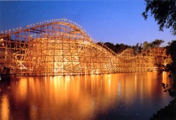 Pegasus bij nacht, geheel uitgelicht. Voor de komst van de Vliegende Hollander weerspiegelde de houten rollercoaster prachtig in het stille water van de Kanovijver.