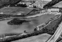 Luchtfoto van de <a href="/lemma/Siervijver" title="Siervijver">Siervijver</a> met daaraan het <a href="/lemma/Cafe-restaurant" class="mw-redirect" title="Cafe-restaurant">Cafe-restaurant</a>, de <a href="/lemma/Speelweide" title="Speelweide">Speelweide</a> met provisorisch voetbalveldje, het net geopende (en daardoor te dateren) <a href="/lemma/Secretariaat" title="Secretariaat">Secretariaat</a> nabij de oorspronkelijke <a href="/lemma/Ingang_Noord" title="Ingang Noord">Ingang Noord</a>. De latere plek van de entree is hier nog bossages en een dienstweg. Linksboven de werkplaats van de <a href="/lemma/Technische_Dienst" title="Technische Dienst">Technische Diensten</a>, het tegenwoordige <a href="/lemma/Efteling_Museum" title="Efteling Museum">Efteling Museum</a>. Helemaal bovenin het <a href="/lemma/Kinderbad" title="Kinderbad">Kinderbad</a> en het <a href="/lemma/Kinderspoor" title="Kinderspoor">Kinderspoor</a>.