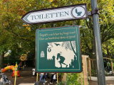 <a href="/lemma/Toilet" title="Toilet">Toilet</a>-wegwijzer bij de <a href="/lemma/Kleuterhof_(1994)" title="Kleuterhof (1994)">Kleuterhof (1994)</a>, aansluitend op het <a href="/lemma/Wereld_van_Sindbad" title="Wereld van Sindbad">Wereld van Sindbad</a>-thema met figuur met lange baard en tulband die in nood naar een toilet schuifelt; in de lucht hangt <a href="/lemma/Vogel_Rok" title="Vogel Rok">Vogel Rok</a>.