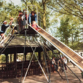 Rechte glijbaan in de <a href="/lemma/Speeltuin" title="Speeltuin">speeltuin</a> in de jaren 80. Op de achtergrond de <a href="/lemma/Ponymanege" title="Ponymanege">Ponymanege</a> - Foto: Irma Verhees {{intern|Gebruikt met toestemming}}